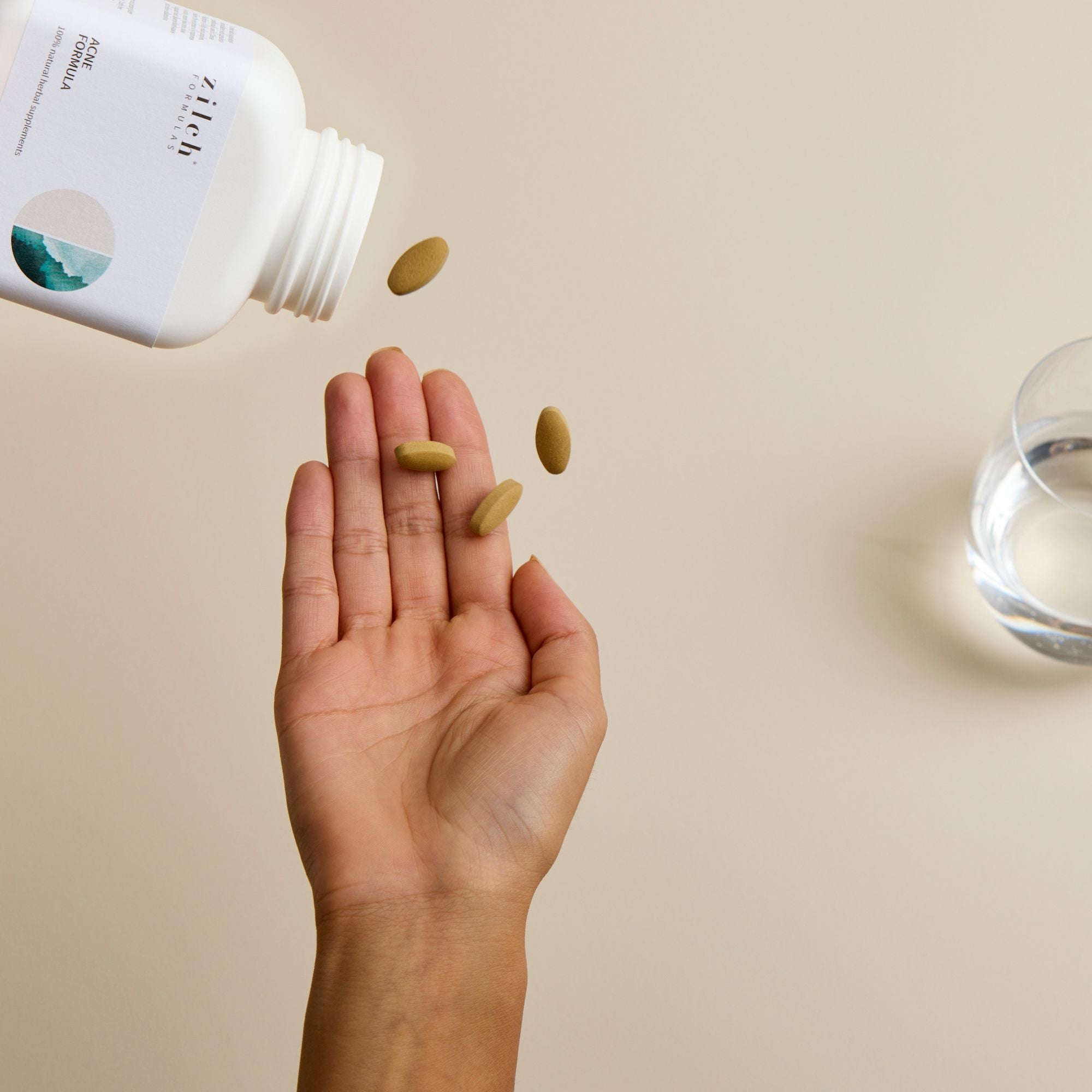 tablets pouring into hand from zilch acne formula bottle