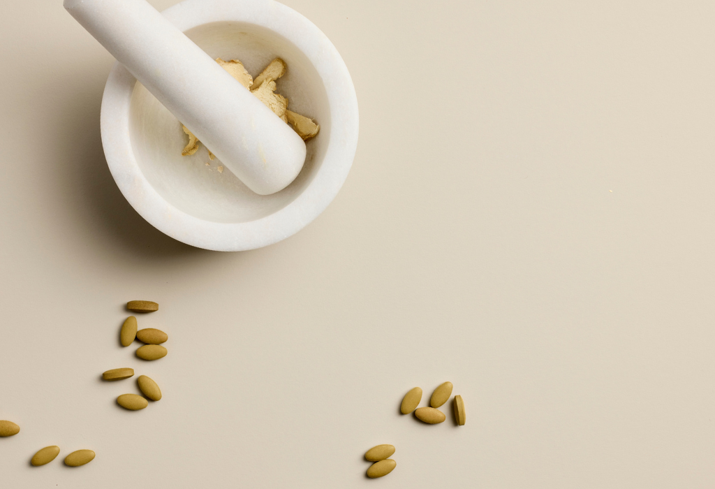 Herbal medicine ingredient inside mortar and pestle with some herbal supplement tablets